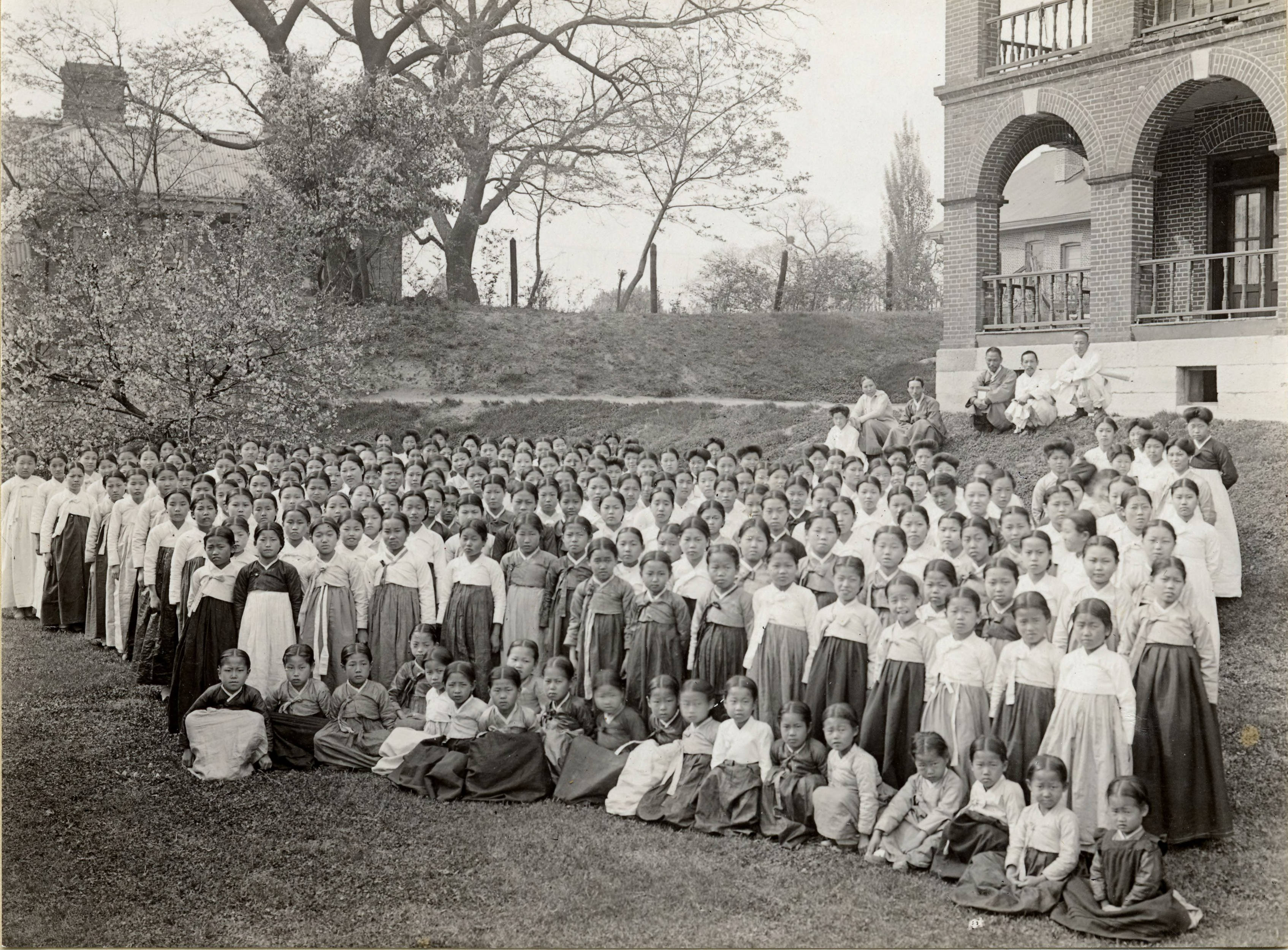 A large group of Ewha Hakdang students posed outside the school building, Seoul, early 20th century